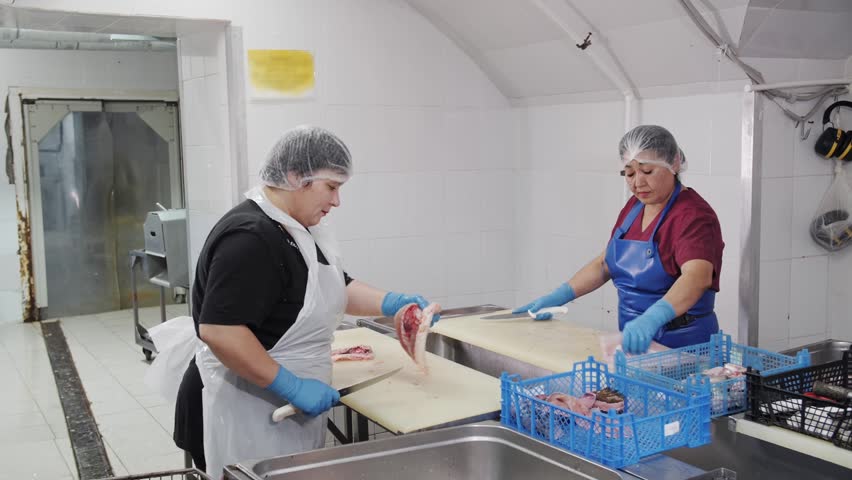 Professional workers processing fresh fish in food factory