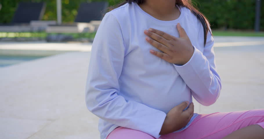 Youth female placing hands on chest belly practicing breathing and singing at poolside with headset. Pool, outdoor, headphones, breath, vocalize, calm, serene