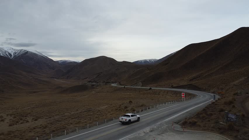 Drone aerial view of curved road through mountain landscape in New Zealand.
