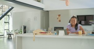 African American mother entering right guiding child for homework at kitchen island with tablet. Caregiver, learner, learning, study, touchscreen, modern, bright - Powered by Shutterstock - Get 15% off with code: PIKWIZARD15