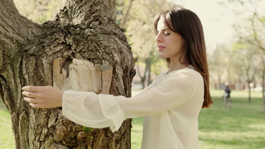 Young woman hugging a tree with eyes closed