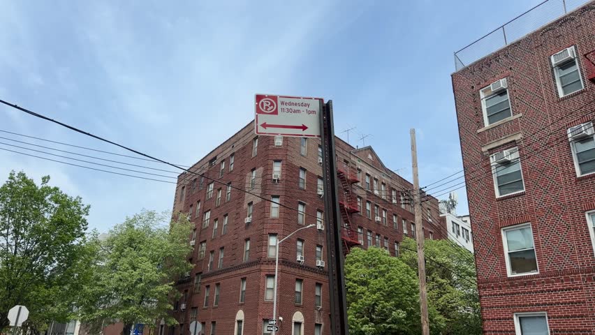 New York City Alternate side parking street sign in urban city area. Traffic regulation sign with parking rules on city street against residential or commercial buildings background