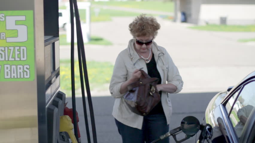Woman discovers she doesn't have enough money to pay for gas.  Medium shot with