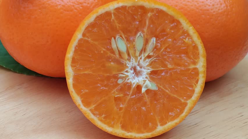 Oranges cut in half with leaves on a wooden tray.