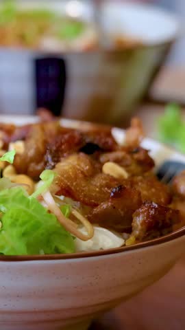 Close-up shot of a hand holding a bowl of Vietnamese grilled pork rice noodle salad