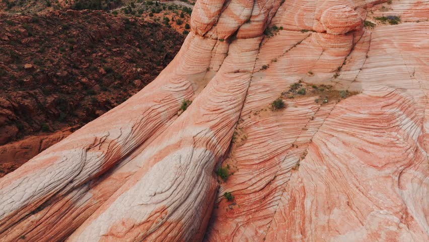 Aerial view of unique red and white striped rock formations with sparse vegetation in the desert near Hanksville, Utah, United States.