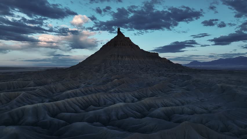 Aerial view of Factory Butte and badlands under a cloudy sky at twilight Wayne County, Utah, United States.