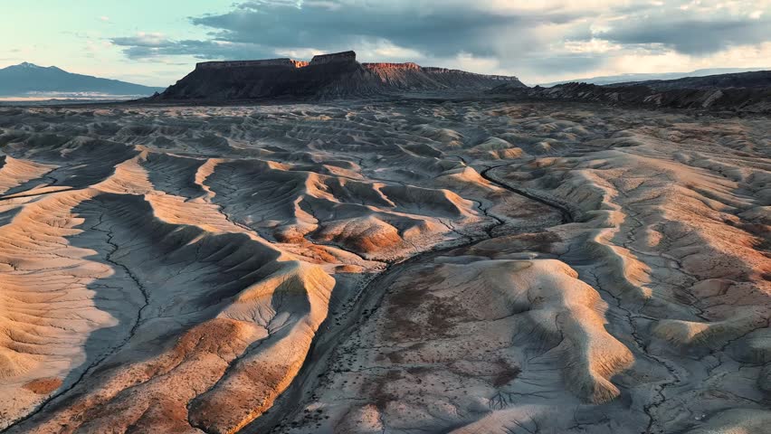 Aerial view of Factory Butte rising above the eroded ridges and dramatic badlands of the desert landscape in Wayne County, Utah, United States.