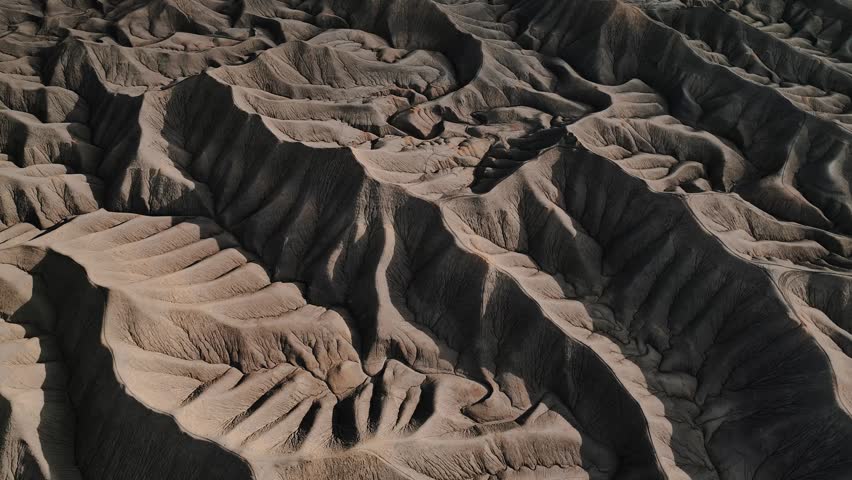 Aerial view of the intricate eroded ridges and deep shadows of the Factory Butte badlands in Wayne County, Utah, United States.