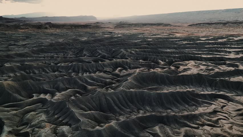 Aerial view of the dark eroded ridges of Factory Butte badlands in Wayne County, Utah, United States.