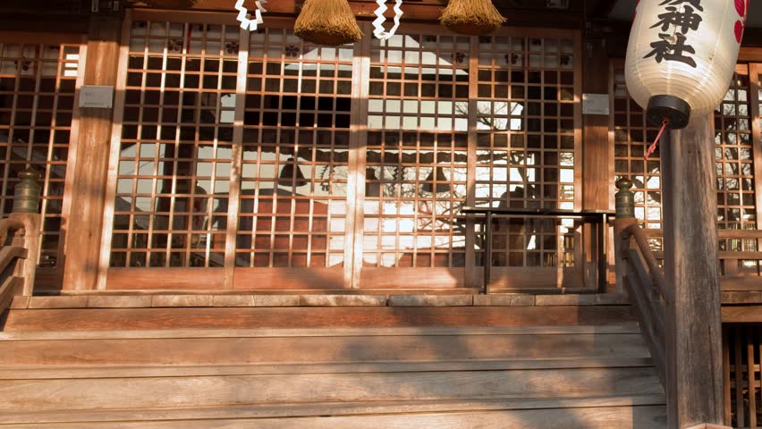 Static medium shot of a Japanese Shinto shrine with paper lanterns and shimenawa rope