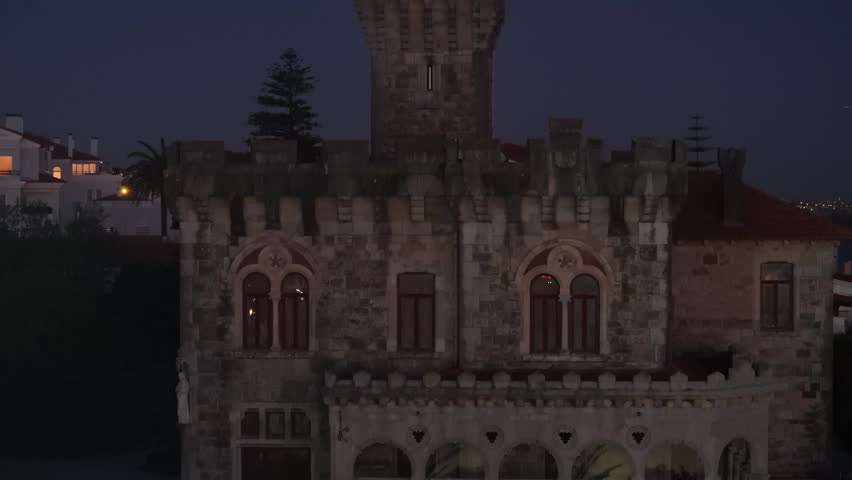 Aerial view of the historic Forte da Cruz castle at night with its illuminated stone facade and tower in Estoril, Lisbon, Portugal.