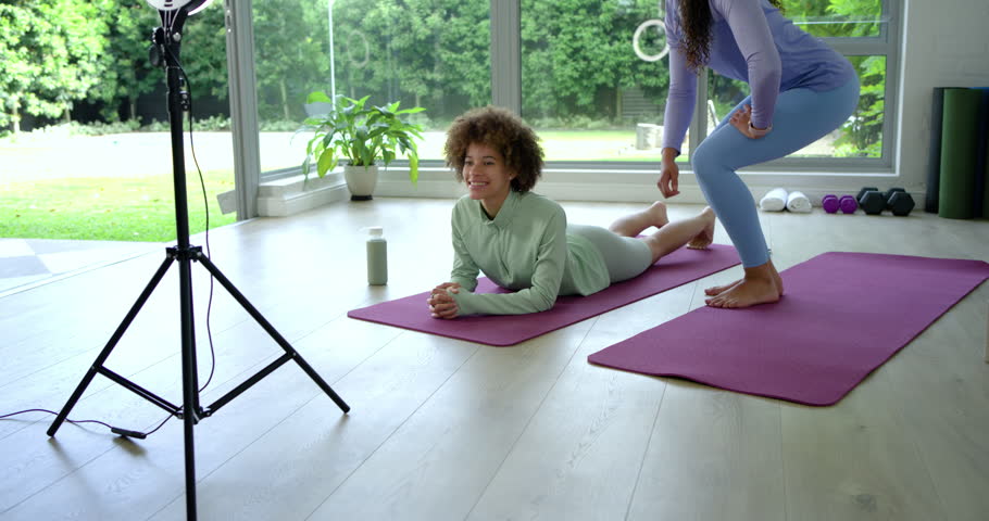 African American women coach, trainee after cue, trainee holding plank, coach aligning hips, tripod. Fitness, home, studio, training, mat, equipment, ringlight