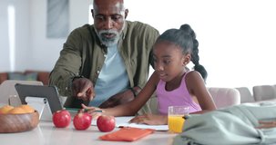African American senior man guiding school child, pointing tablet, 3 apples while teaching counting. Learning, education, tutoring, home, kitchen, numeracy, math - Powered by Shutterstock - Get 15% off with code: PIKWIZARD15