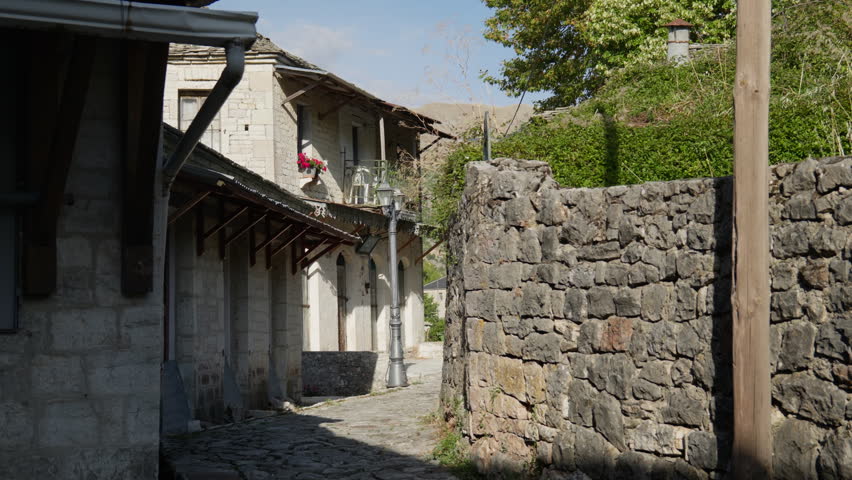 A quaint stone alleyway lined with traditional buildings in Kalarites, Greece. Ideal for travel documentaries or historical architecture features.
