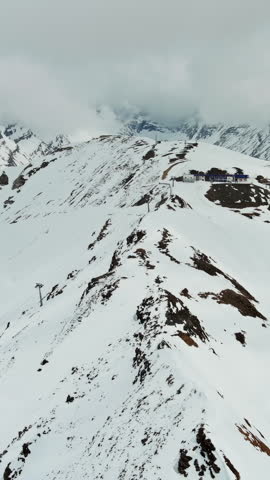 Aerial view of snow mountain range and ski station. Alps mountains, Austria. Vertical video 4k