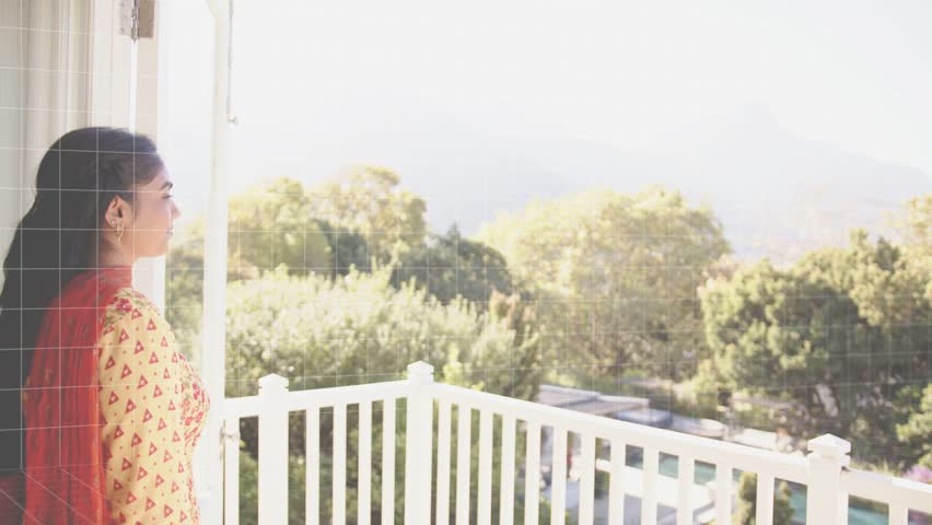 Woman viewing hills at door, timed tech overlay obscuring rail and trees keeping woman visible. Balcony, digital, pixel, binary, landscape, sunlight, mosaic