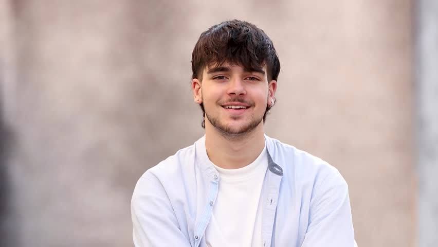 portrait of a young man looking to the side and at the camera outdoors