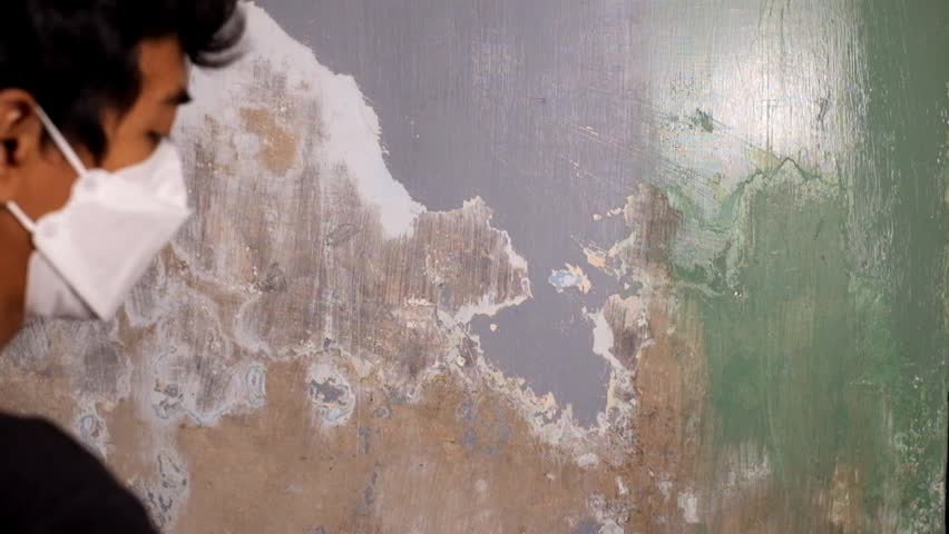 Middle aged man painting interior wall with green paint. DIY home improvement and renovation project. Focused male painter using a brush in a house