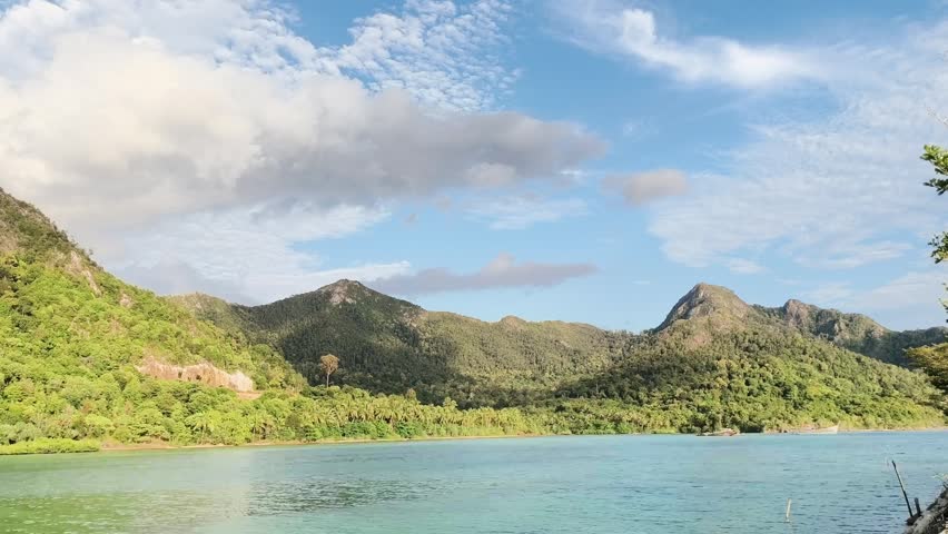A tranquil lake scene with mountains and greenery under a blue sky