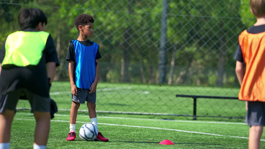 International school student practicing soccer dribbling on the field, improving ball control and individual skills in sports training