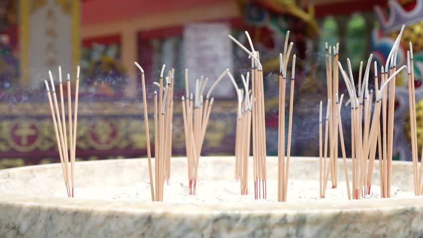 Burning incense sticks with rising smoke in a brass censer at a Chinese temple. People come to pray and pay respect for good luck and peace.