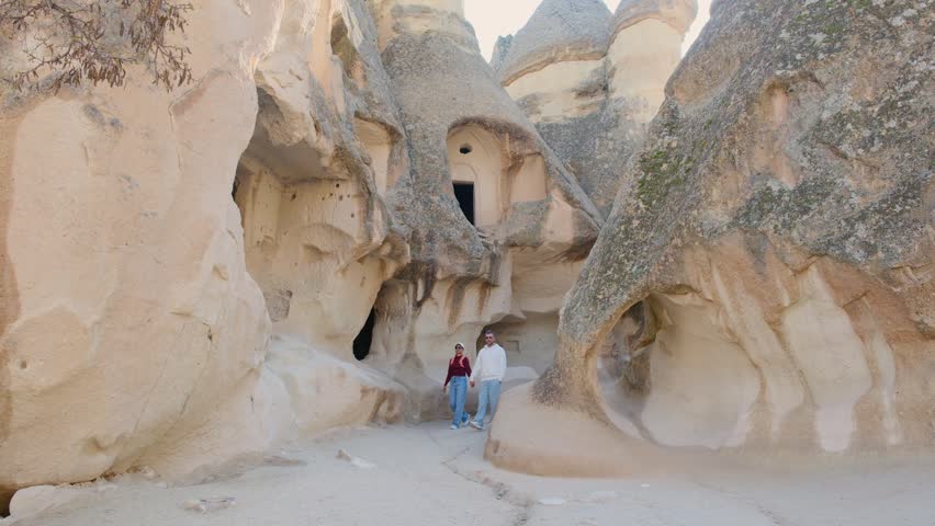 Wander through the stunning rock formations and ancient cave homes in Cappadocia, Turkey. a couple of man and woman visit Pasabag Monks Valley 