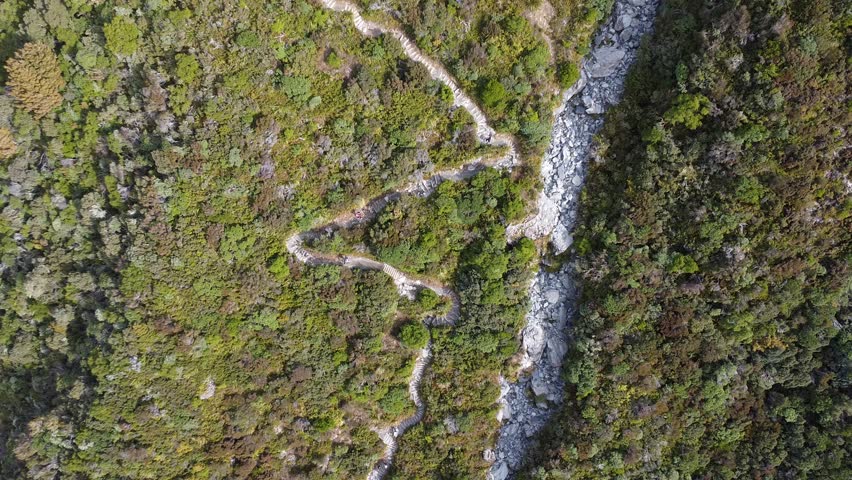 Top down drone view of hiking trail cutting through alpine terrain at Hooker Valley Track, New Zealand.