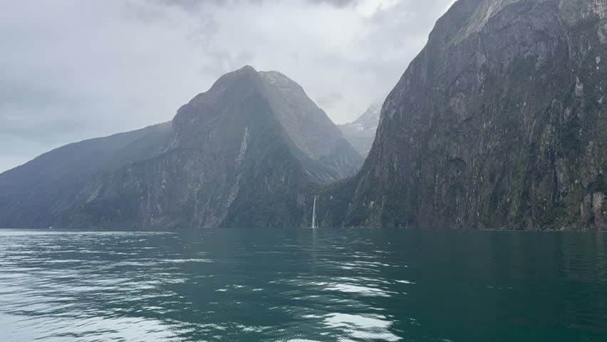Close view of steep cliffs rising from water in Milford Sound fjord, Fiordland, New Zealand.