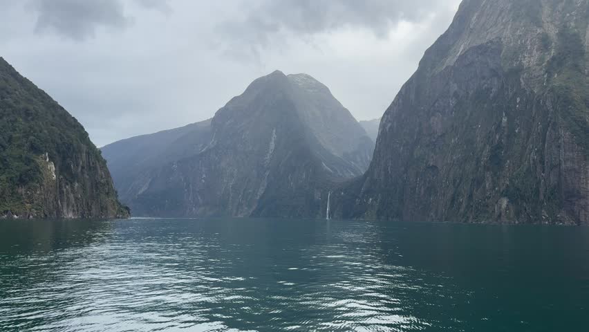 Close view of steep rock cliffs rising from fjord water in Milford Sound, New Zealand.