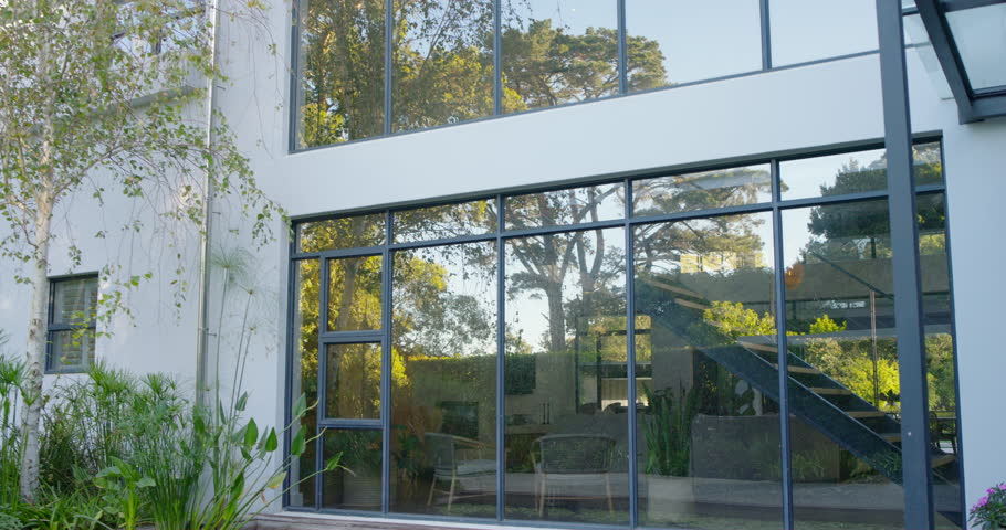 Diverse women arriving at house, agent with tablet pointing and explaining glass facade and pond. Contemporary, modern, home, estate, architecture, water, reflection