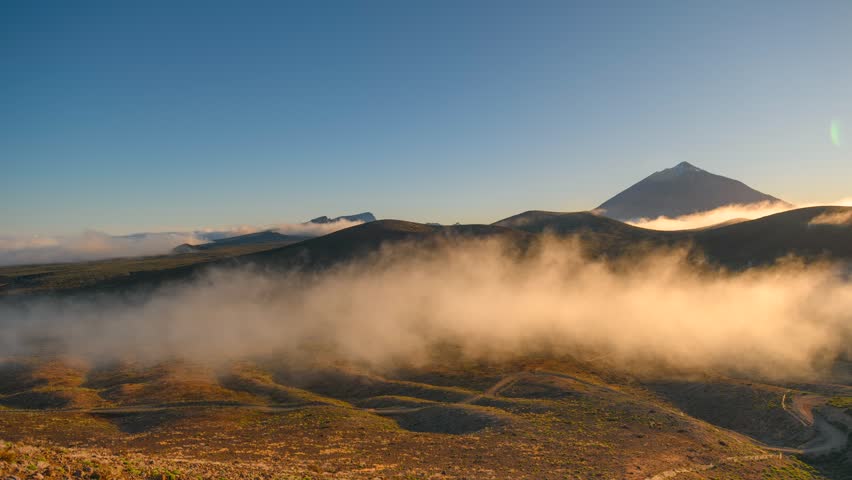 4K time-lapse of golden flowing clouds around mountains at sunrise