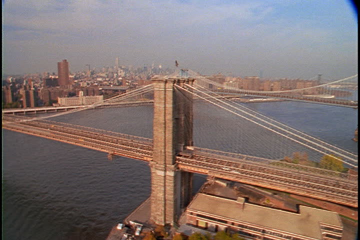  Aerial shot of the Brooklyn Bridge in New York City, USA. The shot follows the span all the way across the river.