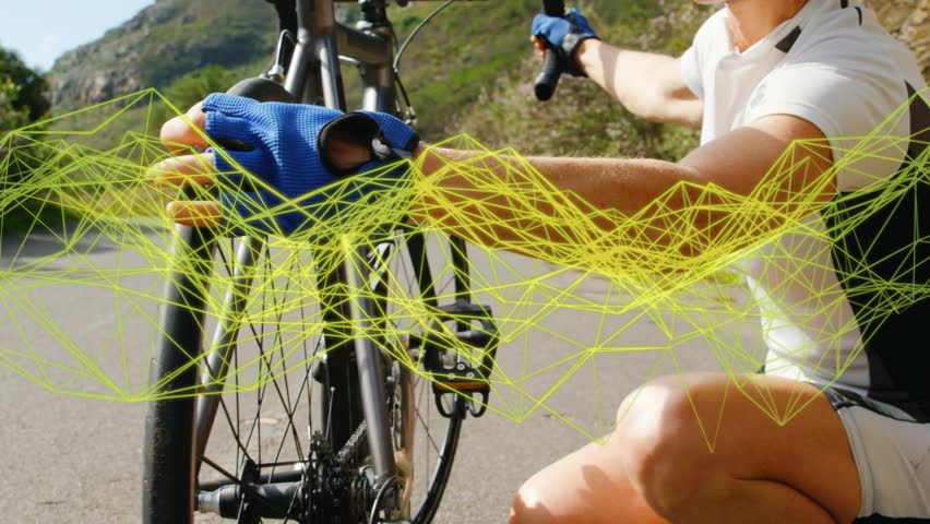 Female cyclist kneeling, checking front wheel before ride on coast road, yellow mesh crossing face. Woman, bike, rider, outdoor, coastal, sunny, asphalt