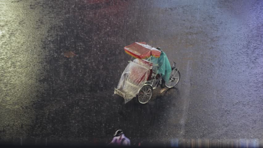 Cyclo driver covered in plastic rides through heavy rain on flooded Hanoi street at night with dramatic lighting and reflections