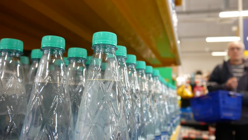 A man takes a bottle of water from a retail display and puts it into a shopping cart