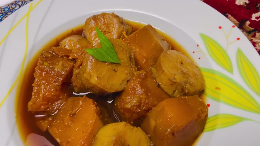 A closeup view of the banana and pumpkin curry with the pandan leaf and palm sugar. This dessert is the Indonesian food that is called as Kolak.