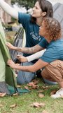 Volunteer, women and pitch tent at summer camp for gear security, outdoor adventure or preparation. Counselor, teamwork and shelter set up on campground for holiday program, assemble rope or safety - Powered by Shutterstock - Get 15% off with code: PIKWIZARD15
