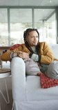 Vertical video: Sitting on sofa at home, man leaning back, gazing window for reflection, copy space. Contemplation, relaxation, modern, cozy, interior, mindfulness, vertical video - Powered by Shutterstock - Get 15% off with code: PIKWIZARD15