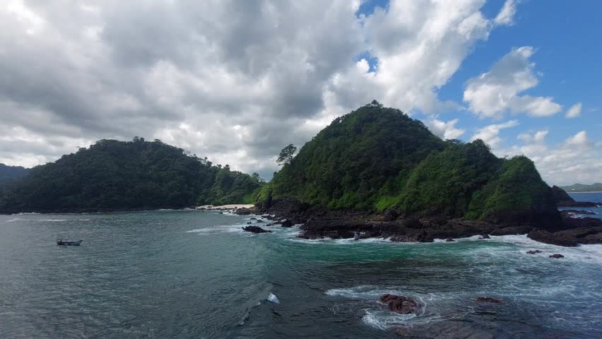 Rocky Tropical Coastline with Waves and Green Hills
