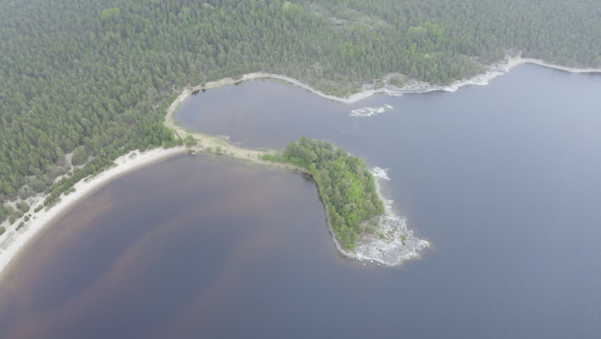 Tilt up aerial shot of Kojonsaari island on Ladoga lake on cloudy summer day. Ladoga Skerries National park, Karelia, Russia.
