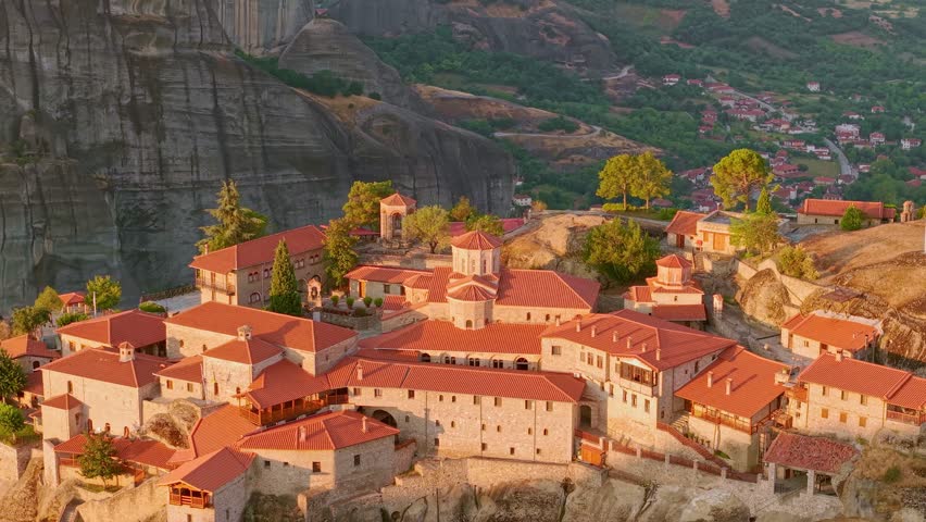 Aerial view of the Holy Monastery of Great Meteoron on a massive rock pillar during a misty sunrise in Meteora, Greece