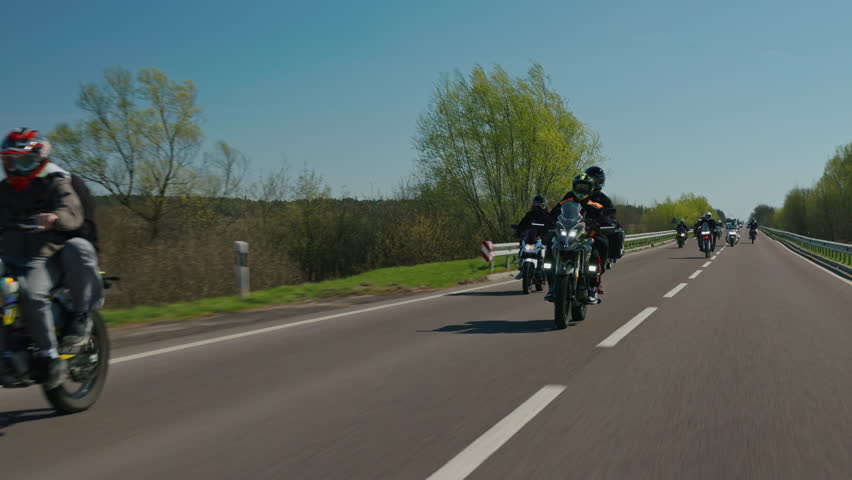 Group of bikers riding on a sunny country road, slow motion