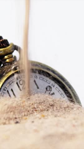 Old alarm clock in sand against white background 4k