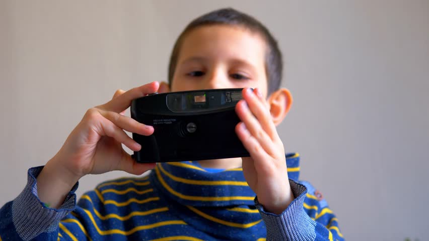 Child Taking Photo with Black Point-and-Shoot Film Camera, Young Photographer Pressing Shutter Button with Flash Firing