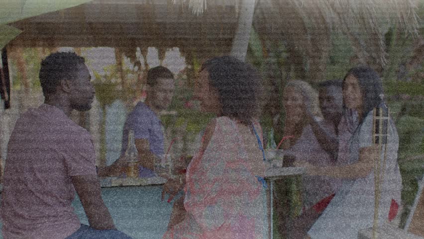 woman in pink wrap touching man in pink tee celebrating leisure animated drinks floating above pair. Tropical, poolside, outdoor, bar, palm, casual, lifestyle