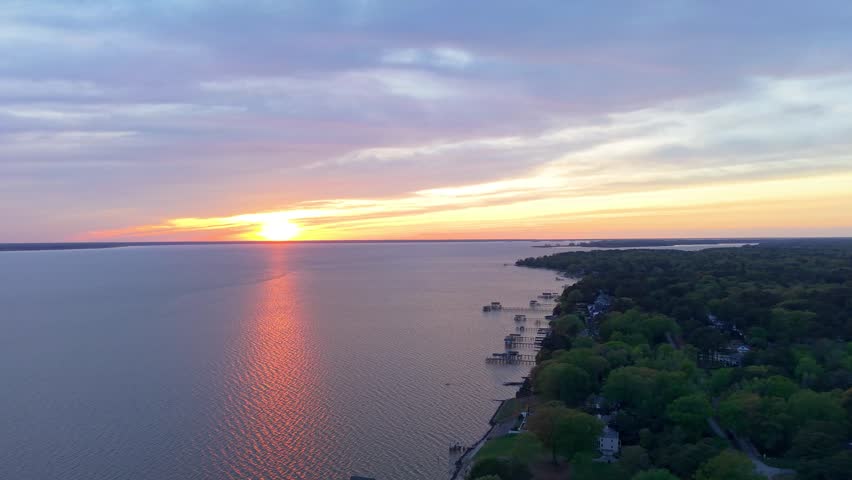 James River coastline in Newport News, Virginia, aerial sunset video, featuring luxury waterfront residential homes and a vibrant evening sky. 