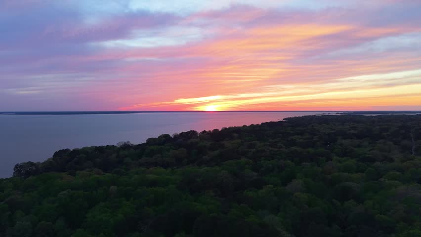 James River coastline in Newport News, Virginia, aerial sunset video, featuring luxury waterfront residential homes and a vibrant evening sky. 