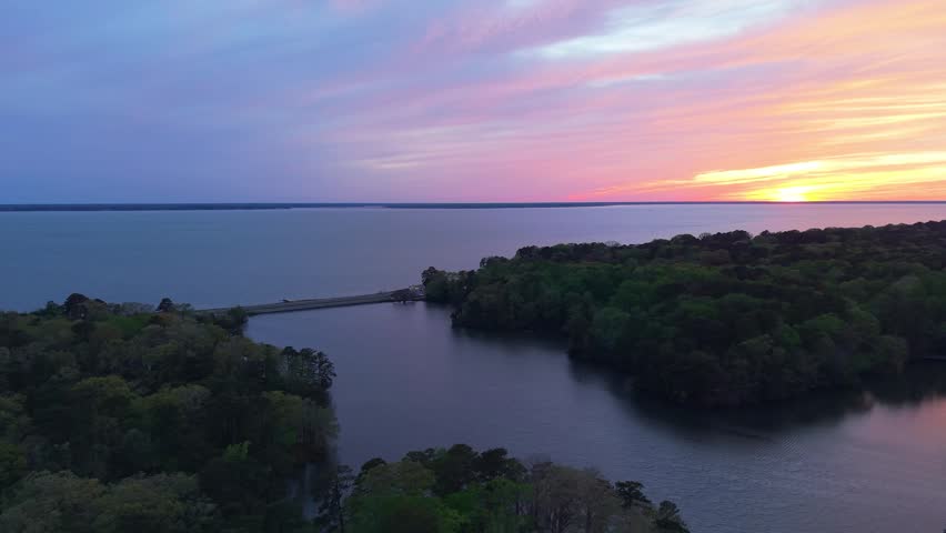 James River coastline in Newport News, Virginia, aerial sunset video, featuring luxury waterfront residential homes and a vibrant evening sky. 
