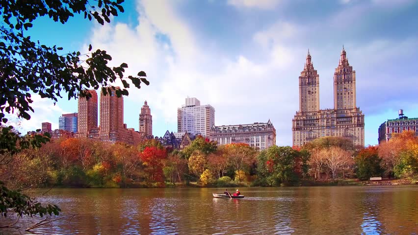 New York. A vivid portrayal of a cityscape during autumn, with a serene lake in the foreground.